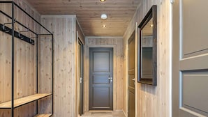Un couloir avec des lambris en bois, une porte et une étagère.