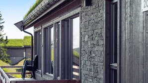 Un bâtiment doté d’une façade en pierre, de grandes fenêtres et d’une terrasse en bois.