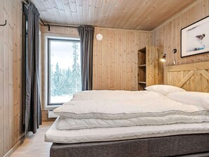 A wooden-paneled room with a bed, a window with curtains, a shelf, and a picture on the wall. - 4 Star Holiday Home in Favang (Ringebu)