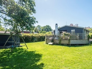 A residential property with a fenced yard, a wooden deck, and a house with a chimney.