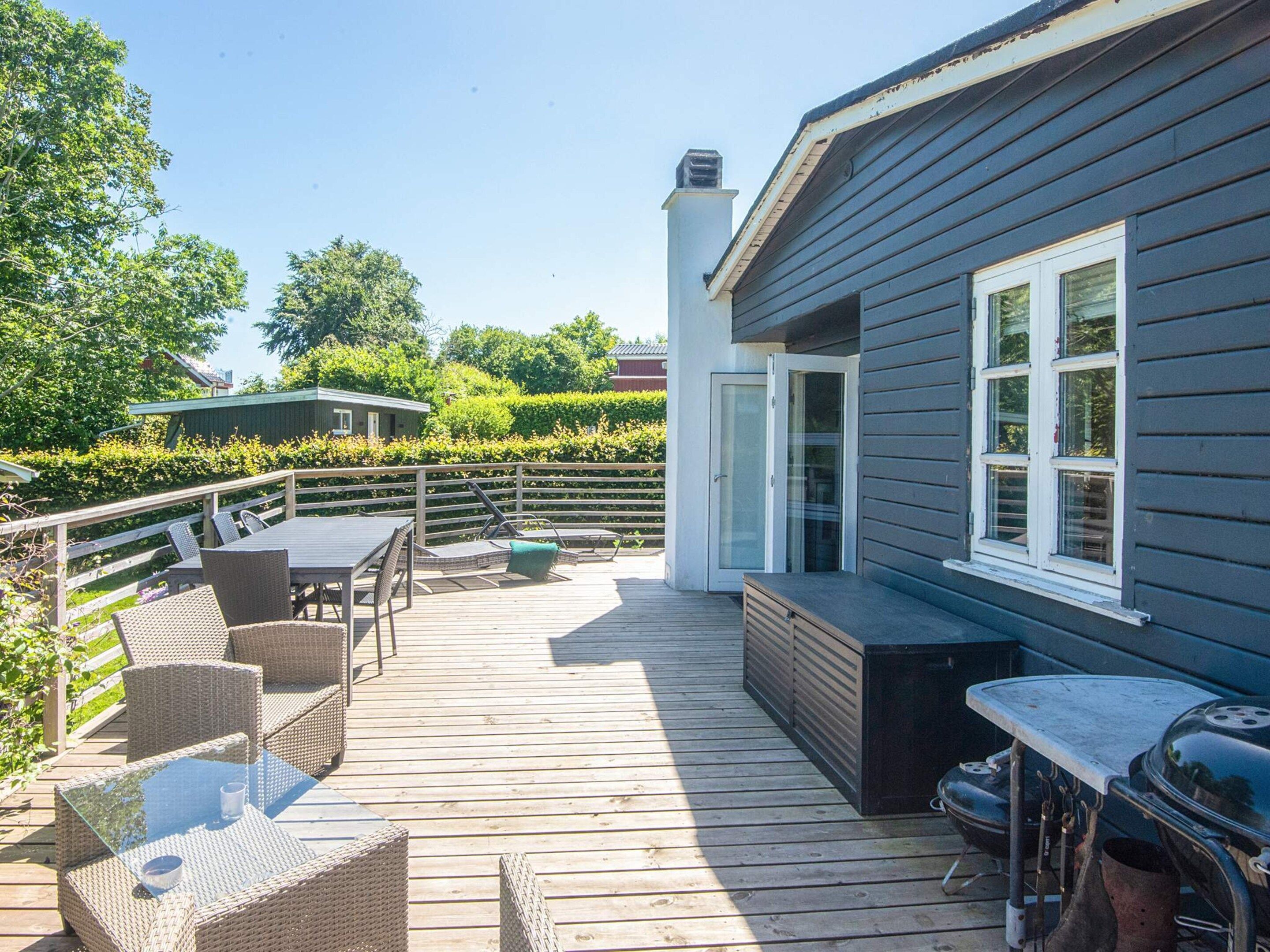 Una terraza con mobiliario exterior, una parrilla y una casa con chimenea.