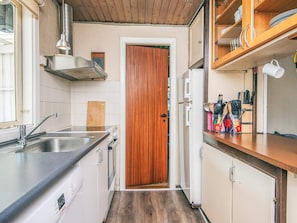 A compact kitchen with a wooden door, stainless steel sink, and a countertop with kitchen utensils.