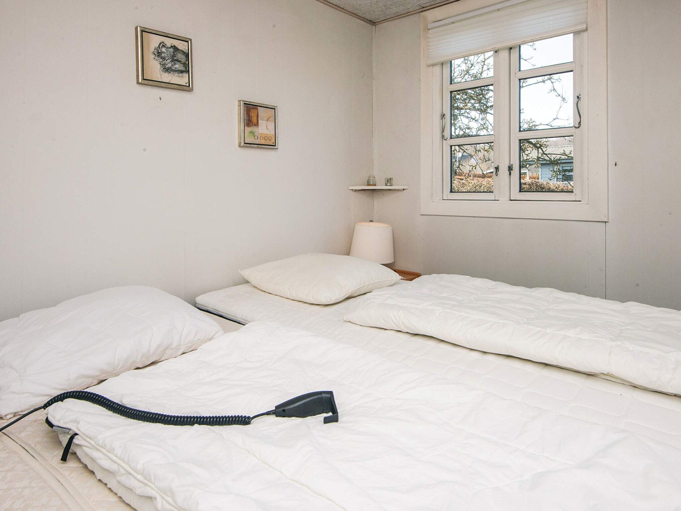 A simple room with two beds, a window, and two framed pictures on the wall.