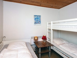 A room with bunk beds, a small table with a lamp, and a framed picture on the wall.