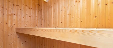 Et sauna rum med trævægge, en bænk og en lampe monteret på væggen.