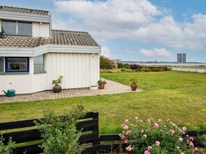 A house with a tiled roof, a paved patio, and a grassy yard with a bench and potted plants. - 6 Person Holiday Home in Ebeltoft (Ebeltoft)
