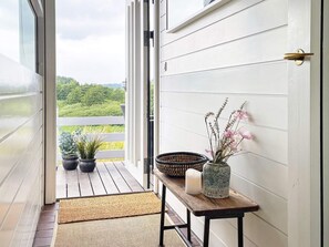 A wooden porch with a bench, potted plants, a candle, and a decorative vase.