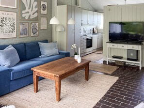 A modern living room with a blue sofa, wooden coffee table, and artwork on the wall. - 5 Star Holiday Home in Aabenraa (Aabenraa)