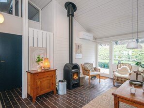 Une pièce chaleureuse avec une cheminée, des meubles en bois et une vue sur la verdure environnante.