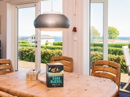 Una mesa de madera para comer con un libro titulado 'Sara Blædel' y una caja decorativa.