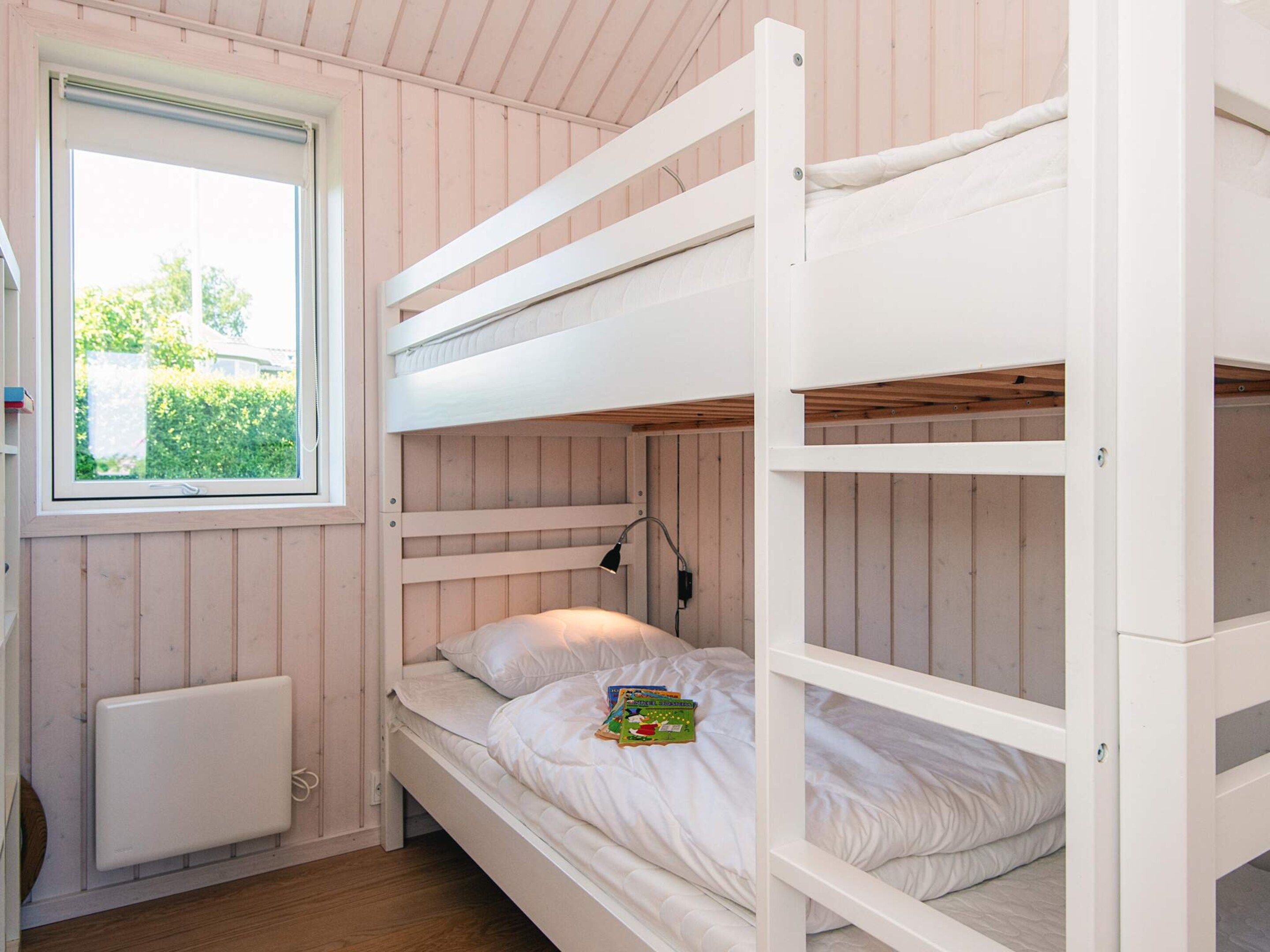 A bunk bed room with a window, a radiator, and a lamp.