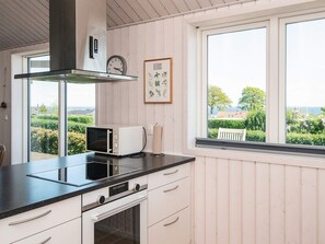 Una cocina con microondas, horno y ventana con vistas a zonas verdes y edificios.