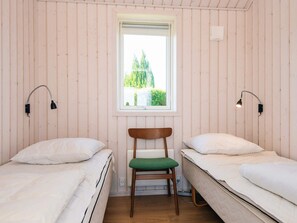 Una habitación con dos camas individuales, una silla, un ventanal con vistas y lámparas de pared.