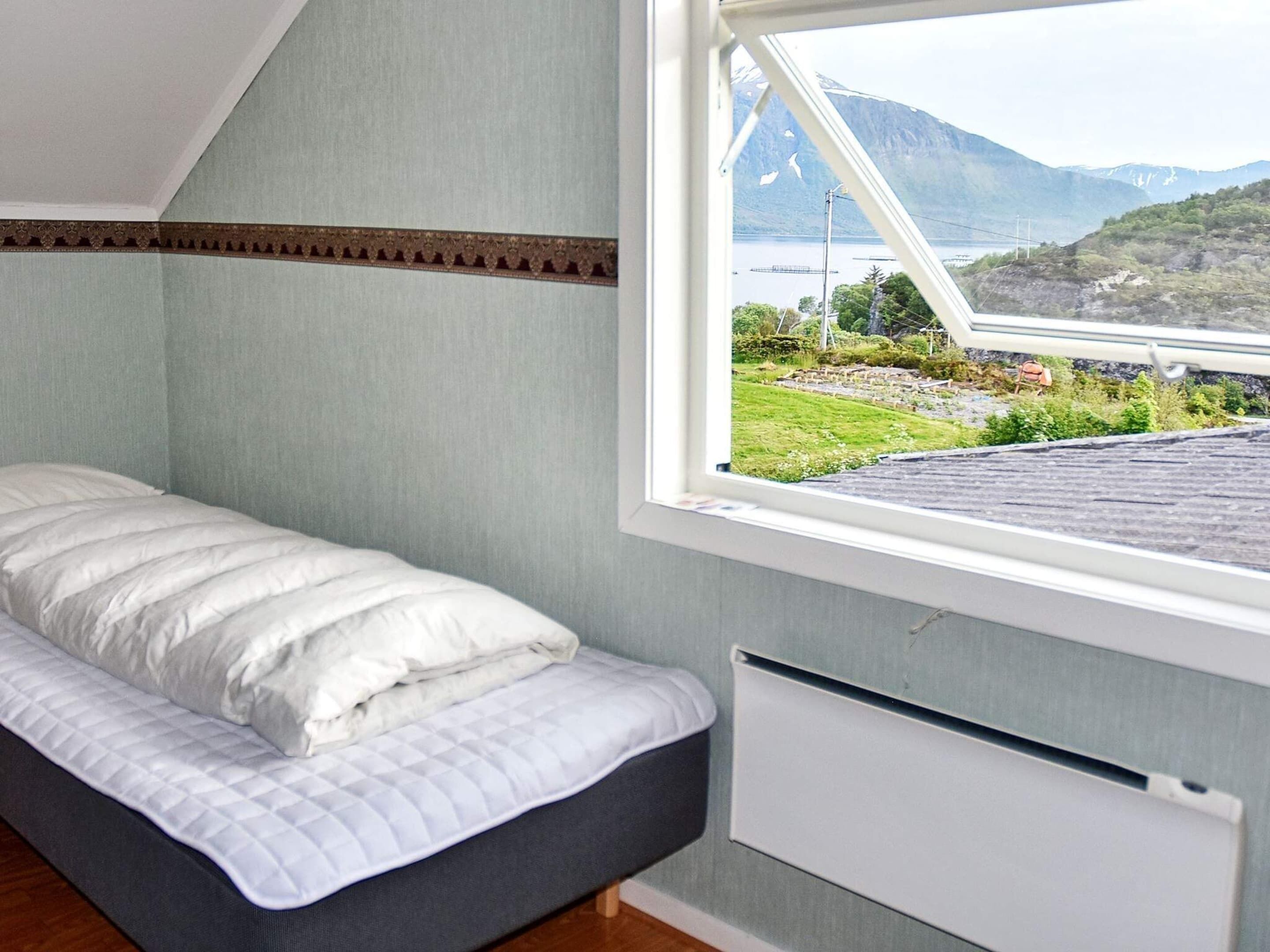 Une chambre avec un lit, un radiateur et une fenêtre donnant sur un paysage.