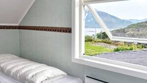 A room with a bed, a radiator, and a window with a view of a landscape.
