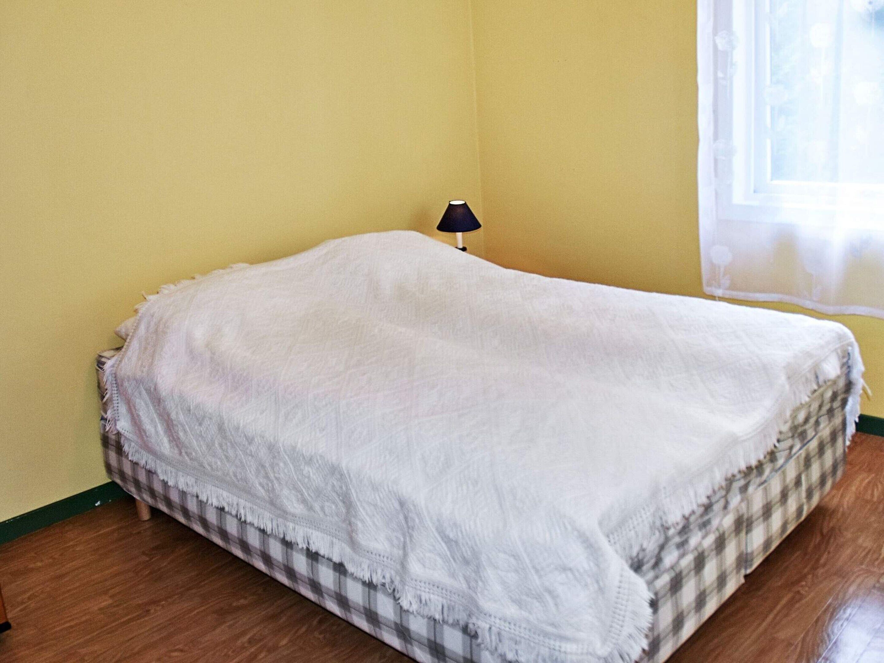 A room with a bed, a lamp, and a window.