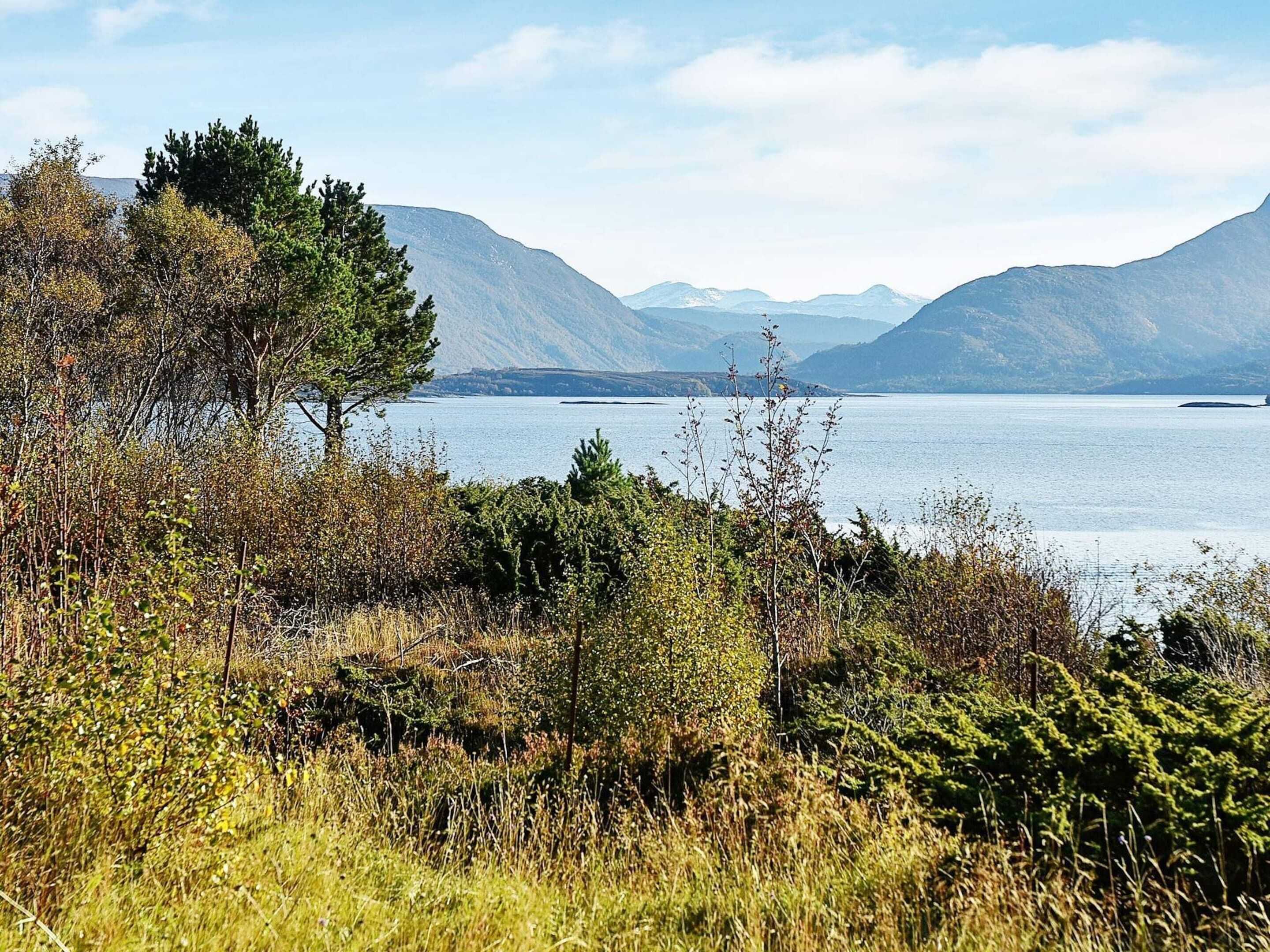 A natural landscape with a lake, mountains, and dense vegetation.