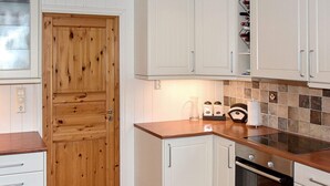 A kitchen with wooden cabinets, a countertop, a stove, and a tiled backsplash.