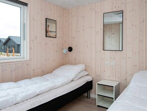 A bedroom with a single bed, a bedside table, a wall-mounted mirror, and a poster on the wall.