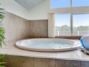 A hot tub in a room with a large window, tiled walls, and a ceiling with a skylight. - 5 Star Holiday Home in Norre Nebel (Norre Nebel)