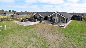 A modern house with a large patio, a hot tub, and a covered outdoor seating area. - 5 Star Holiday Home in Norre Nebel (Norre Nebel)