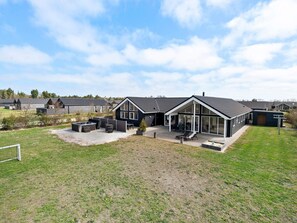 A modern house with a large patio, a hot tub, and a covered outdoor seating area.
