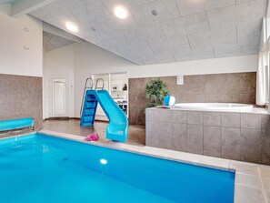 An indoor swimming pool with a blue slide, a hot tub, and a plant. - 5 Star Holiday Home in Norre Nebel (Norre Nebel)