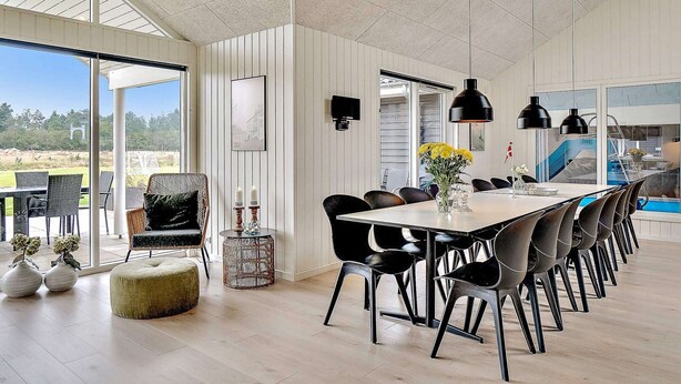 A spacious dining area with a long table, black chairs, and pendant lighting. - 5 Star Holiday Home in Norre Nebel (Norre Nebel)