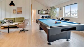 A pool table with balls, a green sofa, and a dining table with chairs. - 5 Star Holiday Home in Norre Nebel (Norre Nebel)