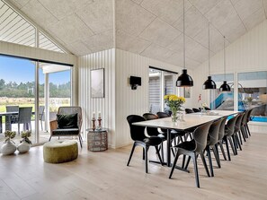 A spacious dining area with a long table, black chairs, and pendant lighting. - 5 Star Holiday Home in Norre Nebel (Norre Nebel)