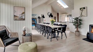 A modern living room with a dining area, a kitchen, and a fireplace. - 5 Star Holiday Home in Norre Nebel (Norre Nebel)