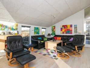 A spacious living area with a black leather sofa set, a wooden coffee table, and colorful artwork on the walls. - 5 Star Holiday Home in Ringkobing (Ringkobing)