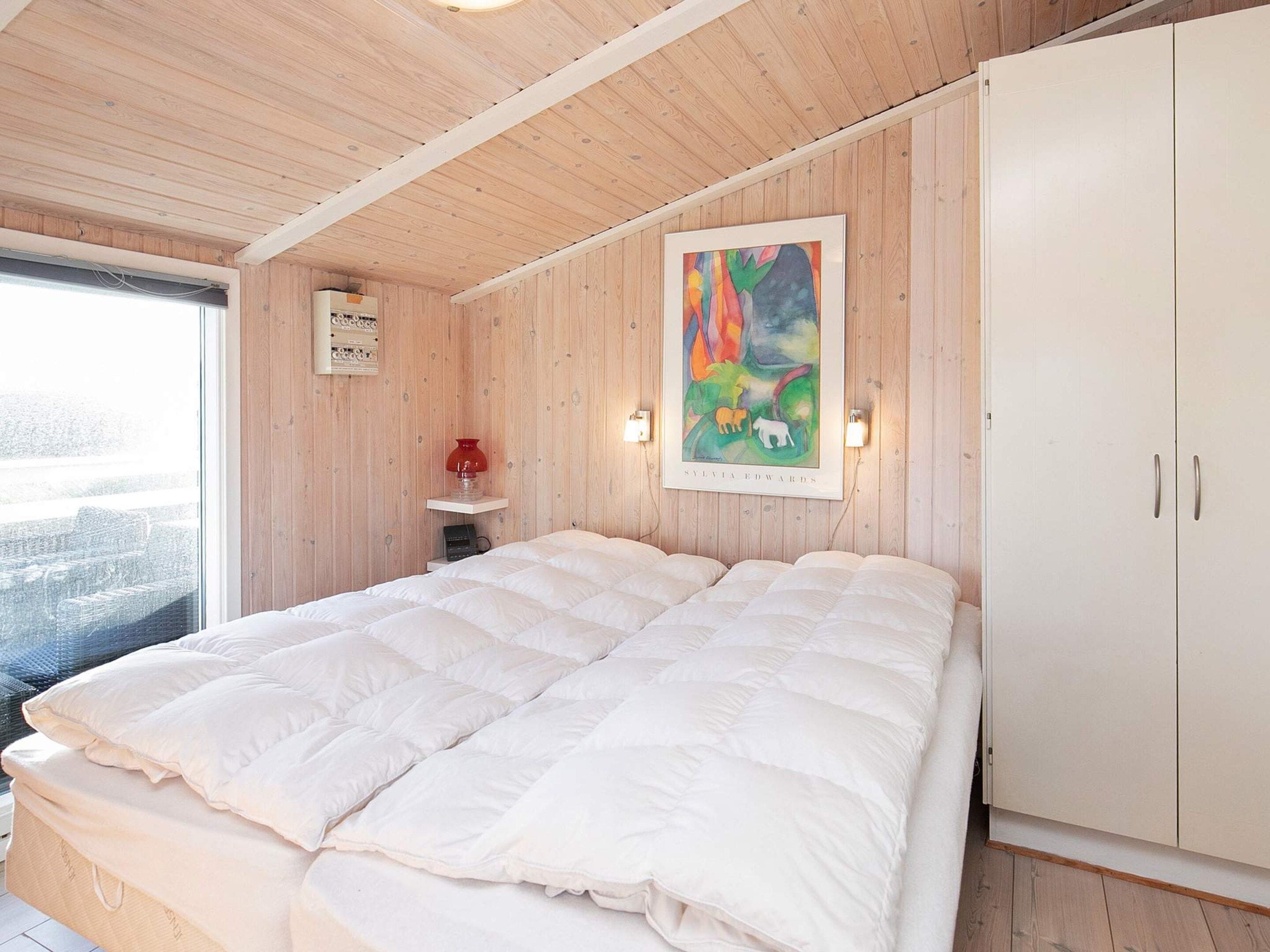 Une chambre à coucher avec un grand lit, des murs en bois, un tableau et une armoire.
