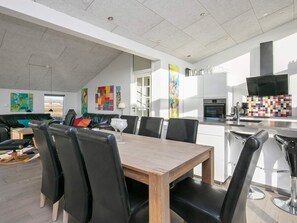 A modern kitchen with white cabinets, a black range hood, and a colorful backsplash. - 5 Star Holiday Home in Ringkobing (Ringkobing)