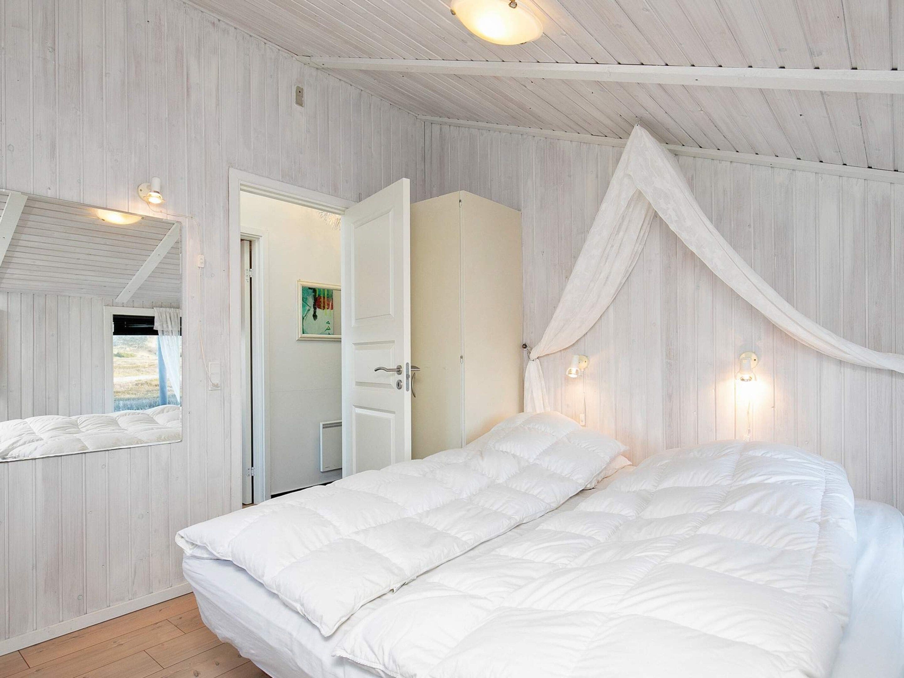 Une chambre à coucher avec un grand lit, une armoire, une porte donnant sur une autre pièce et un baldaquin au-dessus du lit.