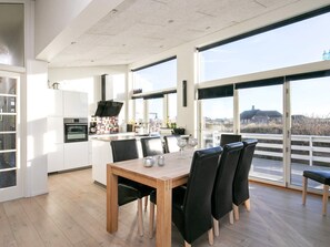 Une cuisine moderne avec un coin repas, de grandes fenêtres et une vue sur la campagne.