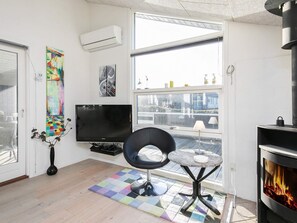 A modern living room with a flat-screen TV, a fireplace, a large window, and a colorful rug. - 5 Star Holiday Home in Ringkobing (Ringkobing)