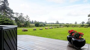 A wooden deck with a view of a grassy field and trees. - 5 Person Holiday Home in Otterup (Otterup)
