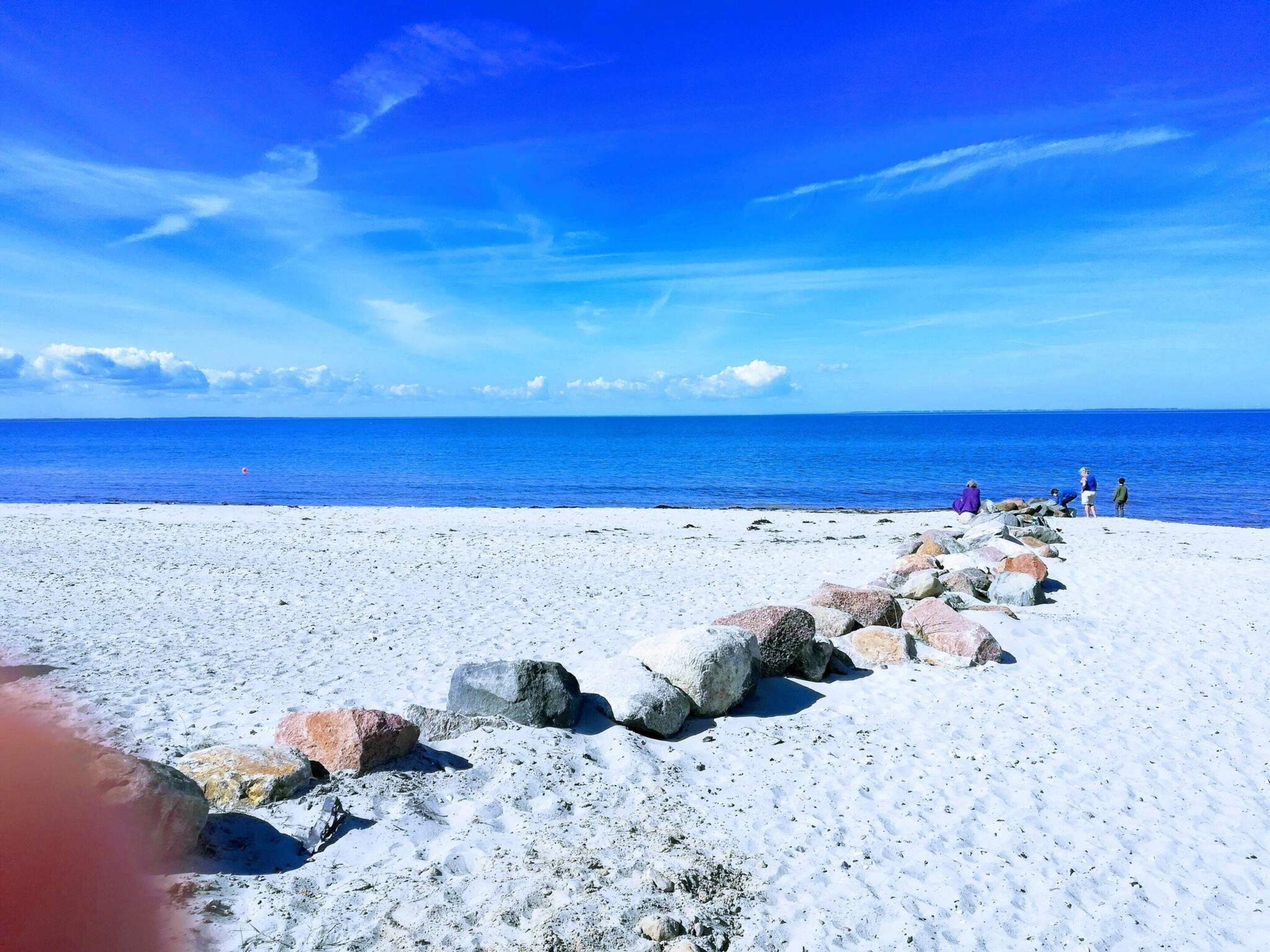 Una playa con una fila de rocas y un cielo azul despejado.