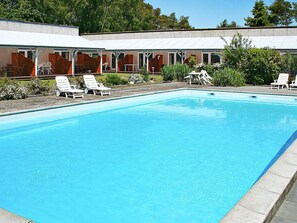 A rectangular swimming pool with white lounge chairs around it. - 4 Person Holiday Home in Nexo (Nexø)