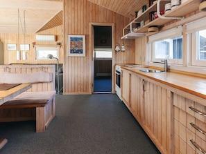A wooden interior with a kitchenette, a bench, and a framed picture on the wall.