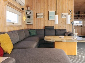 Una sala de estar acogedora con un sofá seccional, una mesa de centro y paredes de madera.
