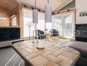 Una sala de estar moderna con un televisor de pantalla plana grande, dos sillones, una mesa de centro y una chimenea.