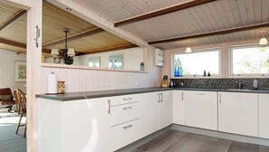 Eine moderne Küche mit weißen Schränken, einer Arbeitsplatte aus Granit und einem Fischgrätparkett.