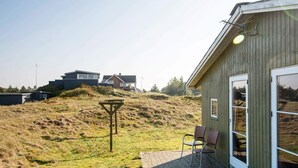 Ein Gebäude mit Holzfassade und einer gepflasterten Terrasse mit zwei Stühlen.