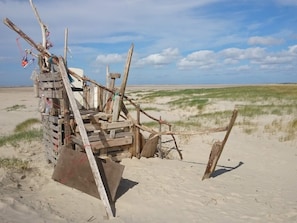 A beach structure made of wooden planks and branches, with a bottle and a flag. - 6 Person Holiday Home in Fano (Fano)