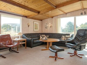 A cozy living room with a leather sofa, a brown leather chair, a wooden coffee table, and a small wooden side table. - 6 Person Holiday Home in Fano (Fano)
