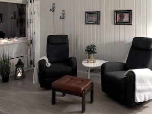 A room with two black armchairs, a small wooden table with a plant, and a brown ottoman. - 9 Person Holiday Home in Svensby (Lyngen)