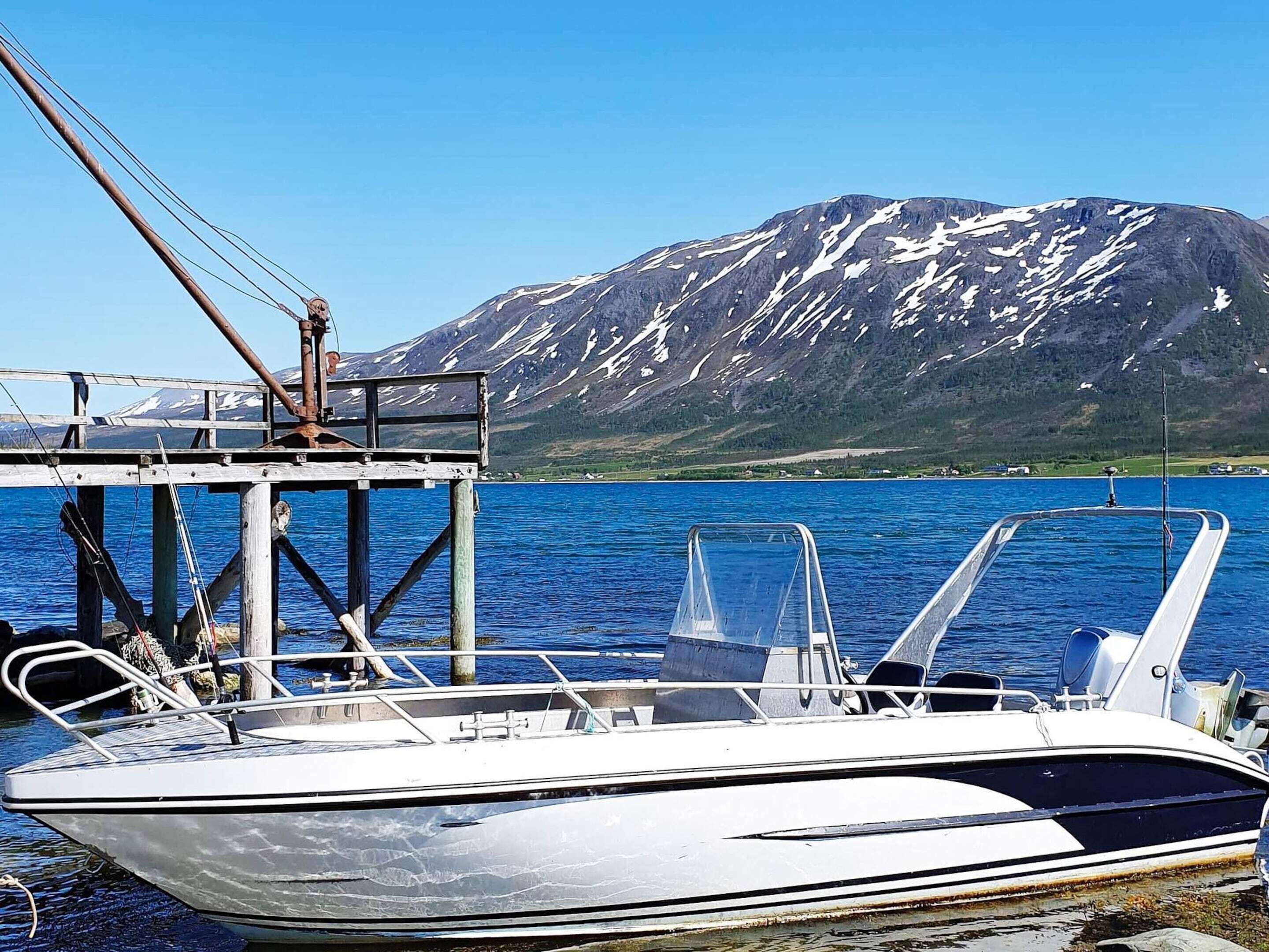A boat docked at a pier with a mountainous backdrop.