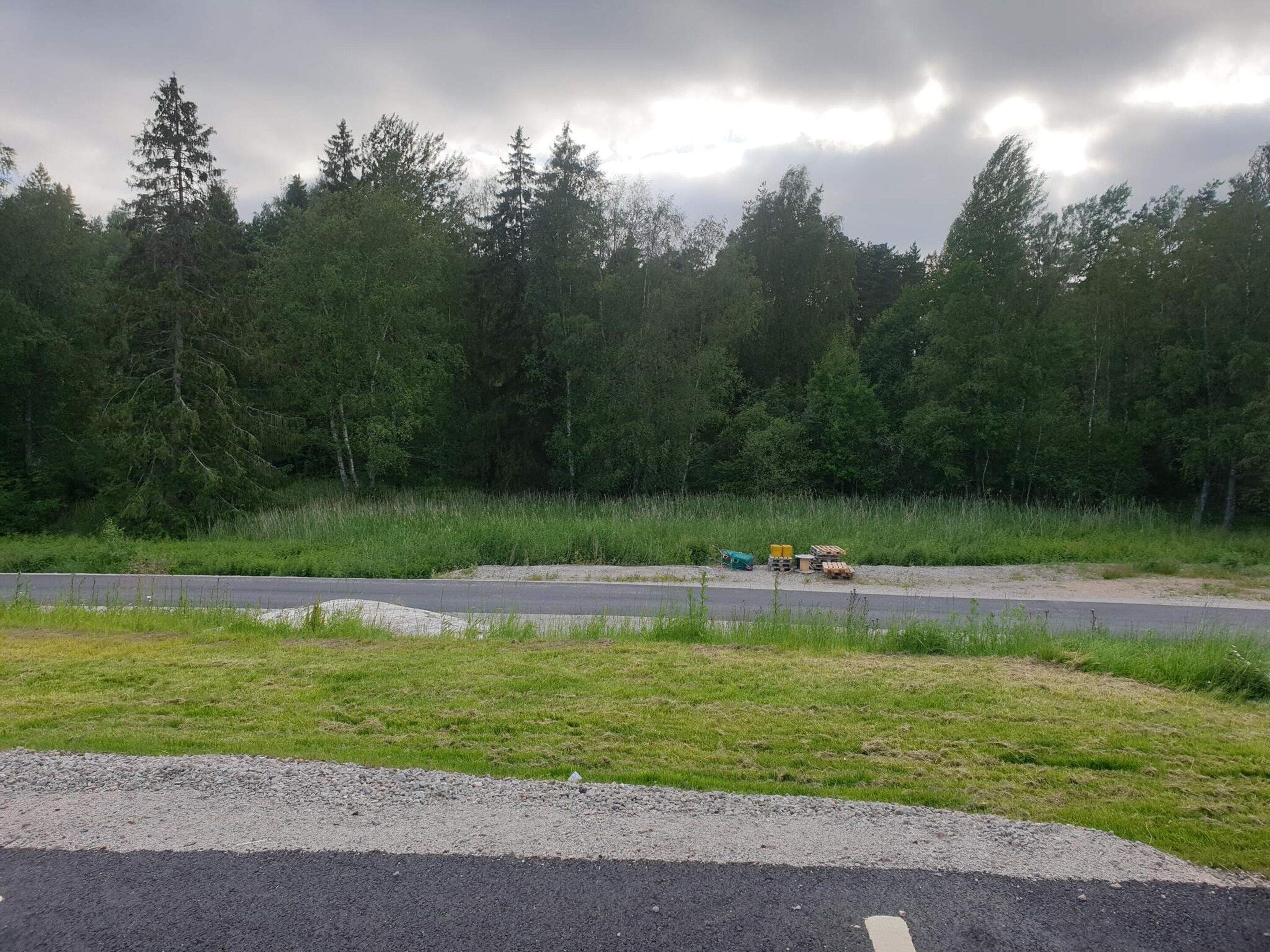 Un área de grava al lado de una carretera con un montón de materiales de construcción.